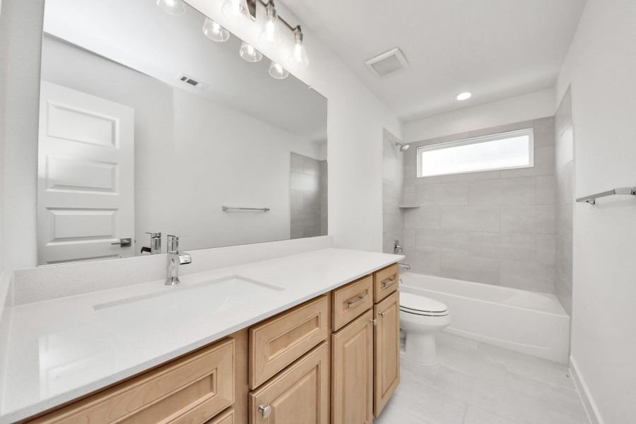 Secondary bath features tile flooring, bath/shower combo with tile surround, light stained wood cabinets, beautiful light countertop. Secondary bath features tile flooring, bath/shower combo with tile surround, light stained wood cabinets, beautiful light countertop.