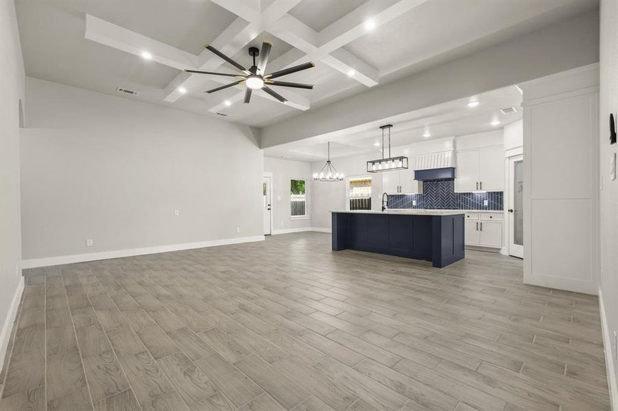 Kitchen featuring open floor plan, coffered ceiling, decorative backsplash, recessed lighting, and a chandelier