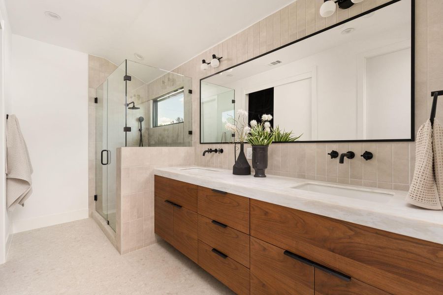 A well-appointed primary bathroom featuring a spacious dual-sink vanity and a sleek glass-enclosed shower.