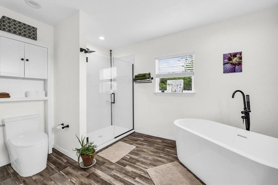 Primary bath featuring a shower stall, a freestanding tub, dark wood-style floors, and recessed lighting