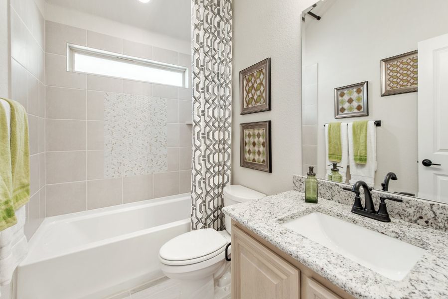 Full bathroom with granite countertop vanity, tiled tub-shower combo, and patterned curtain Full bathroom with granite countertop vanity, tiled tub-shower combo, and patterned curtain