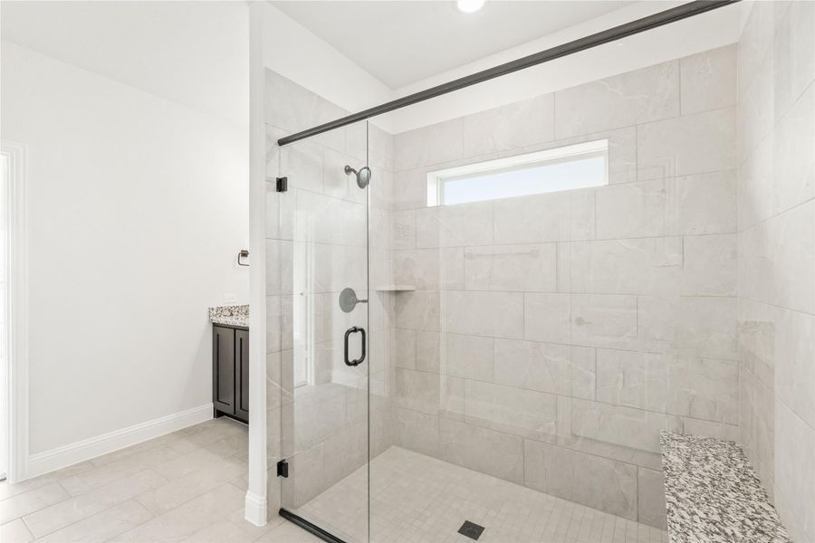 Walk-in shower with large white tile walls, glass door, built-in bench, and small window above Walk-in shower with large white tile walls, glass door, built-in bench, and small window above