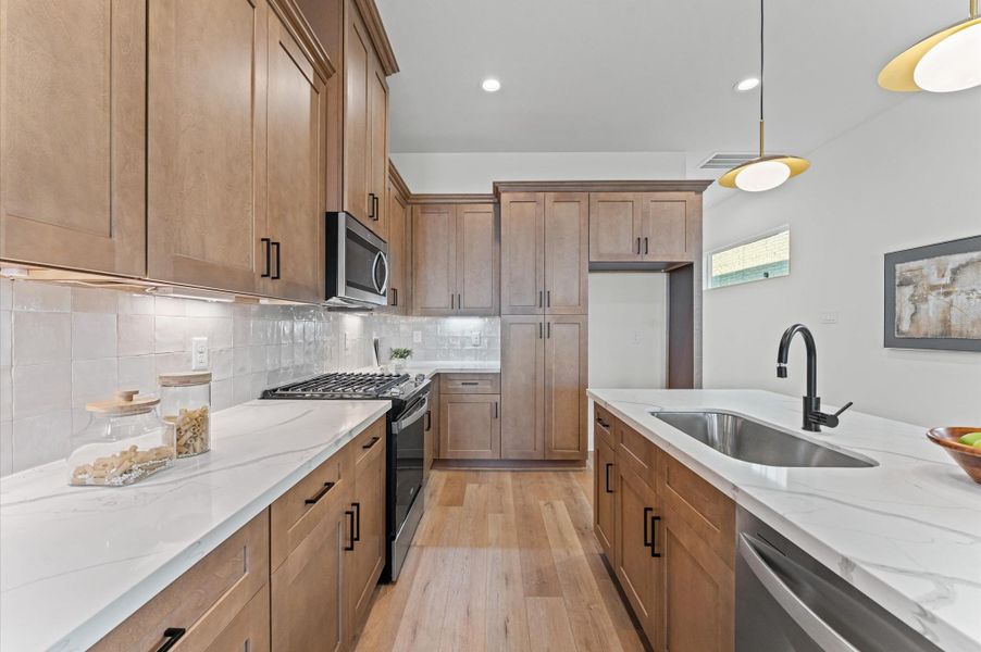 Kitchen boasts stainless steel appliances, shaker cabinets and quartz countertops.