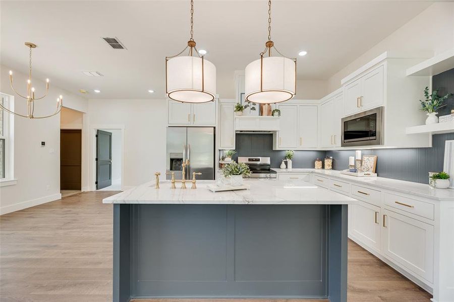 Kitchen featuring white cabinetry, decorative light fixtures, light wood finished floors, appliances with stainless steel finishes, and light stone counters