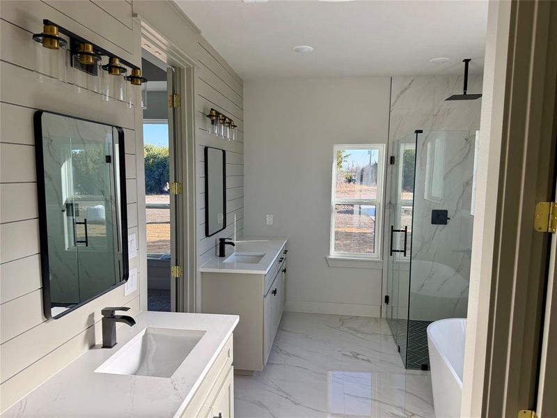 Full bathroom with a marble finish shower, two vanities, light marble finish flooring, and plenty of natural light