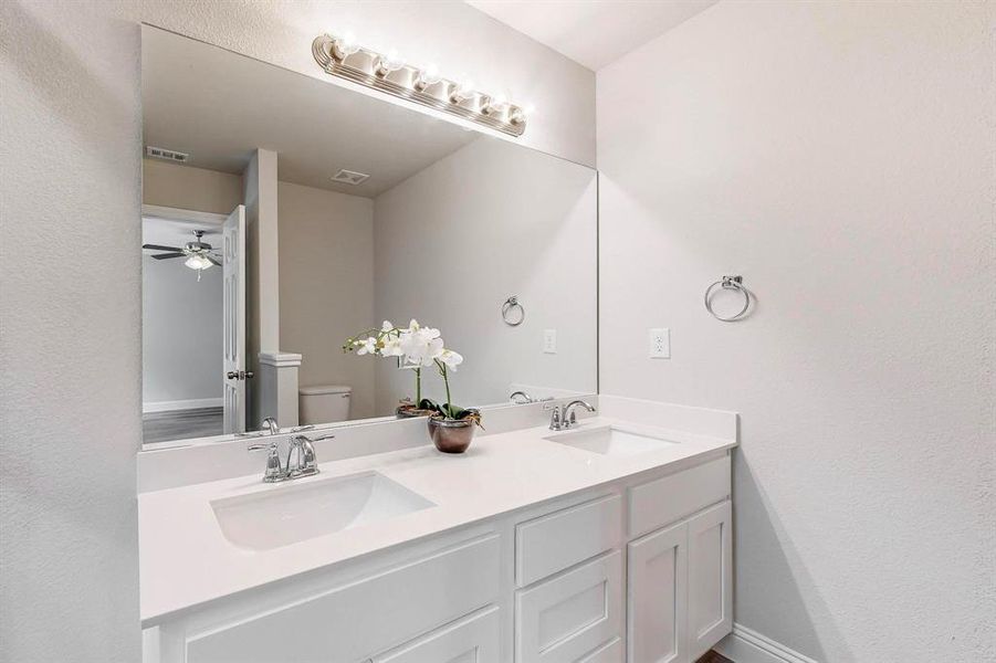 Bathroom featuring ceiling fan, vanity, and toilet