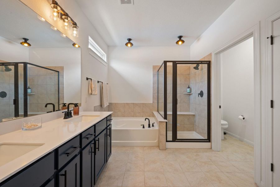 Full bathroom featuring a bath, a stall shower, double vanity, and light tile patterned floors Full bathroom featuring a bath, a stall shower, double vanity, and light tile patterned floors