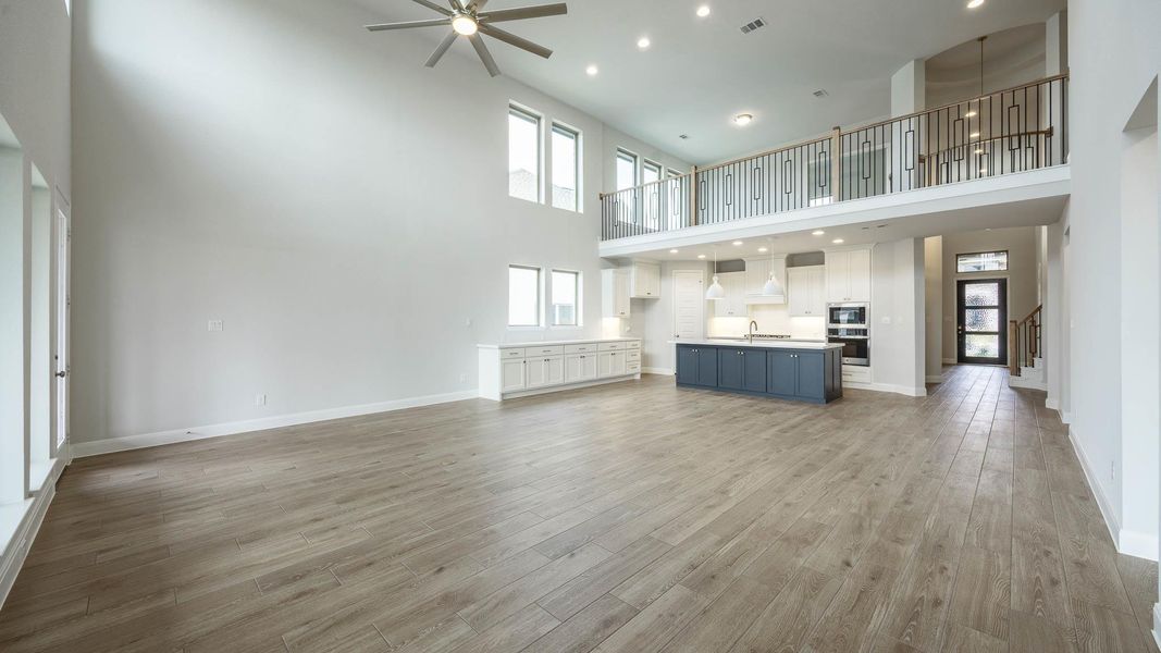 Unfurnished living room featuring recessed lighting, a ceiling fan, light wood-style flooring, and a high ceiling