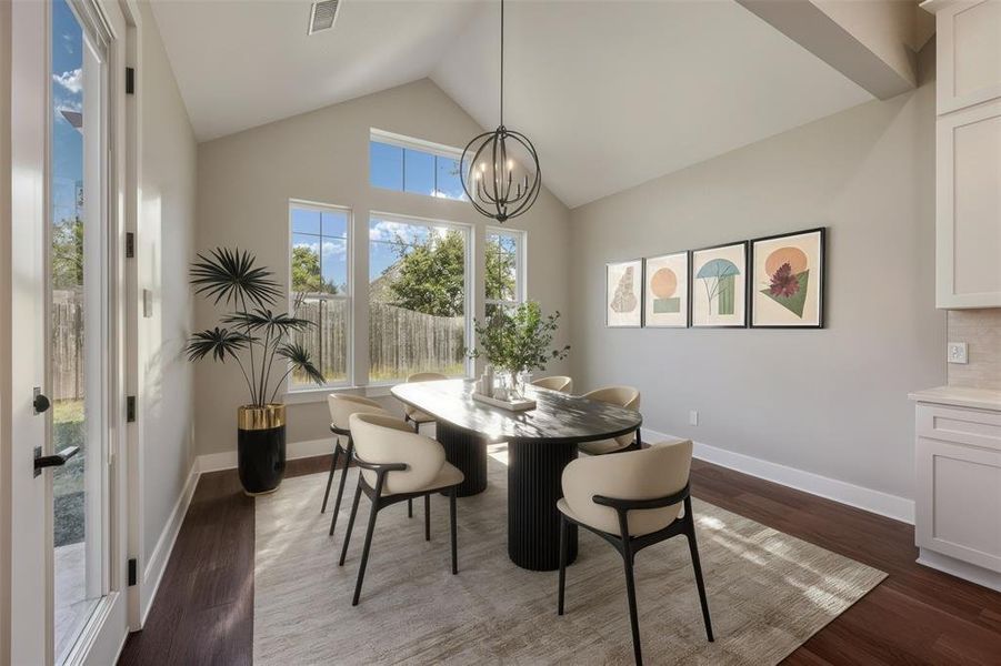 Dining area with dark wood-style flooring, high vaulted ceiling, and a chandelier
