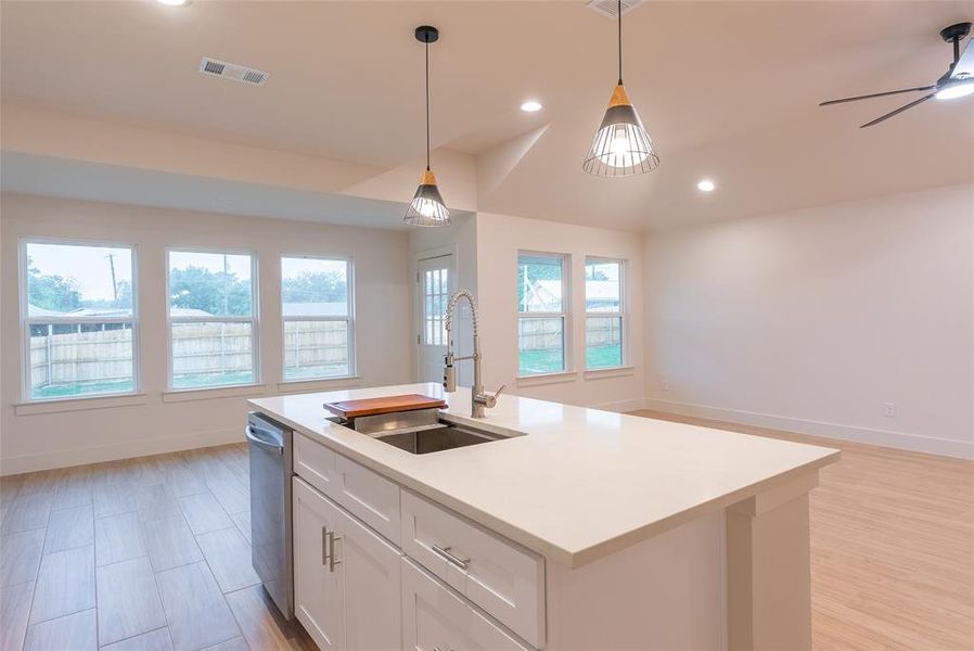 Kitchen featuring open floor plan, white cabinetry, hanging light fixtures, recessed lighting, and light wood-style flooring