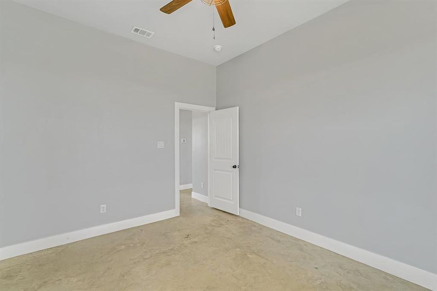 Spare room featuring concrete flooring, ceiling fan, and baseboards