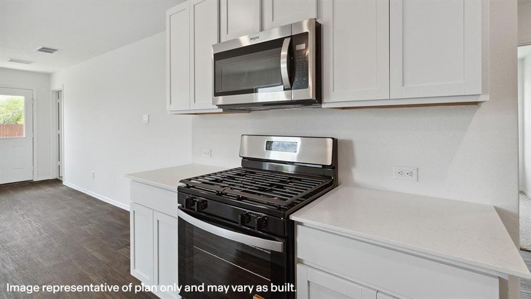 Kitchen featuring stainless steel appliances, dark wood-style flooring, white cabinets, and light stone counters