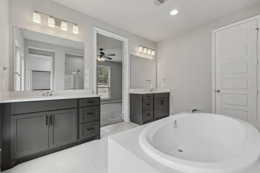 Full bath featuring a bath, two vanities, ceiling fan, a shower, and tile patterned floors Full bath featuring a bath, two vanities, ceiling fan, a shower, and tile patterned floors