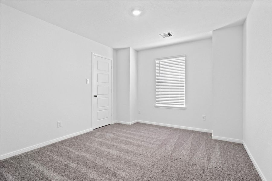 Secondary bedroom, pictured here, features plush carpeting, neutral paint tones, recessed lighting, large window with privacy blinds, and a walk-in closet.