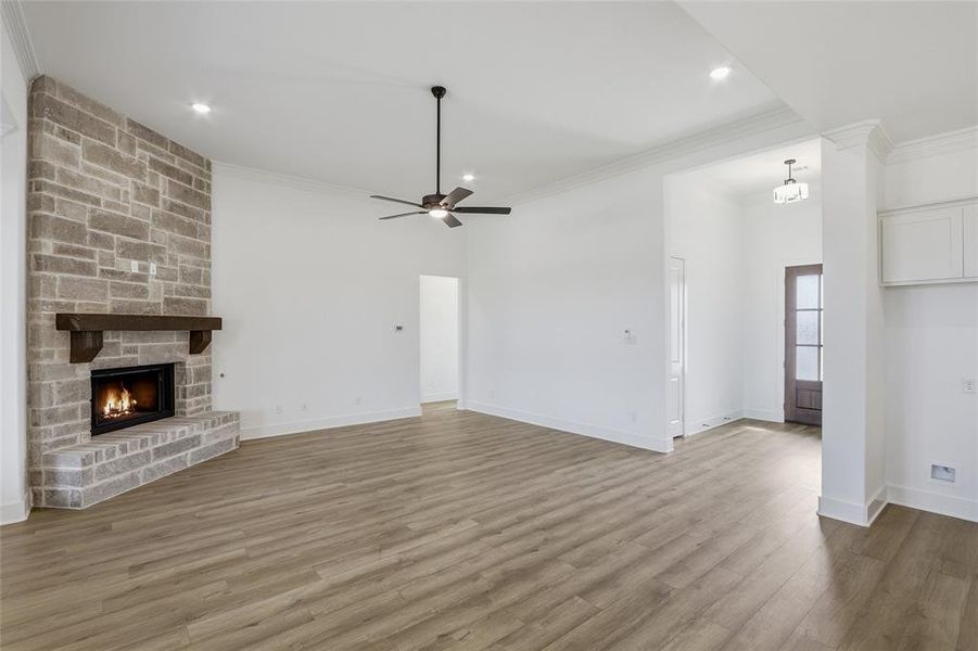 Unfurnished living room with a fireplace, crown molding, ceiling fan, dark wood finished floors, and recessed lighting
