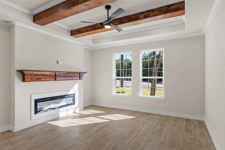 Unfurnished living room with ceiling fan, beamed ceiling, light hardwood / wood-style floors, and ornamental molding