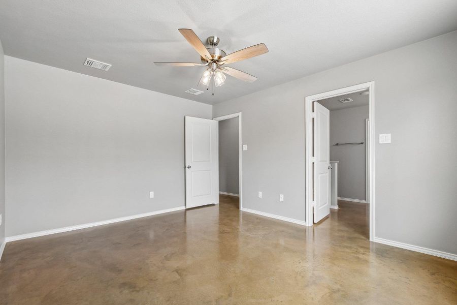 A well-lit bedroom features durable concrete flooring, ready for personalization. A well-lit bedroom features durable concrete flooring, ready for personalization.