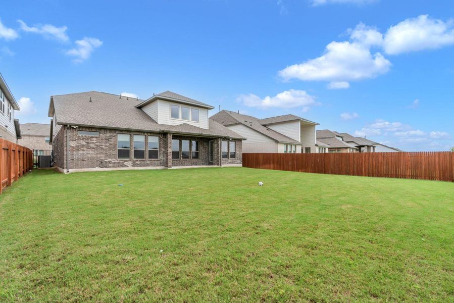 A spacious backyard with vibrant green grass, enclosed by a sturdy wooden fence, awaits new memories.
