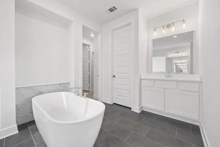 Full bathroom featuring a freestanding bath, vanity, wainscoting, tile patterned floors, and tile walls Full bathroom featuring a freestanding bath, vanity, wainscoting, tile patterned floors, and tile walls