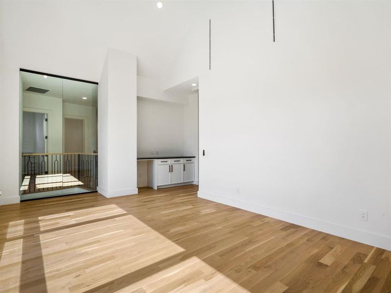 Spare room featuring light wood-type flooring, a high ceiling, and recessed lighting