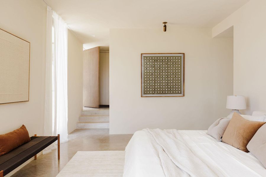 Primary Bedroom with view of pivot door and entrance to rear terrace and resort-style pool.