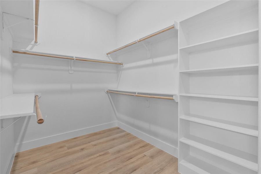 Spacious walk-in closet featuring built-in shelving, abundant hanging space and convenient storage organization. Spacious walk-in closet featuring built-in shelving, abundant hanging space and convenient storage organization.