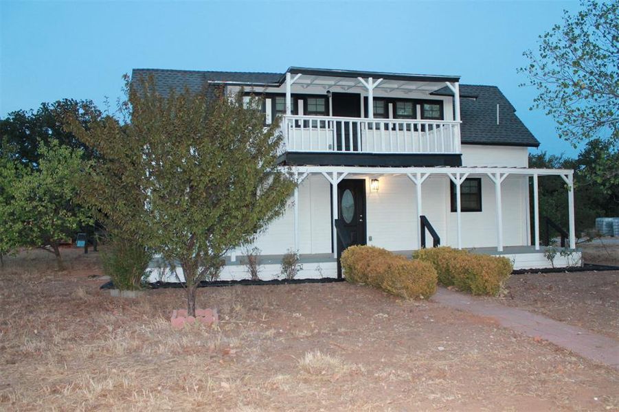 View of front facade with a shingled roof and covered porch
