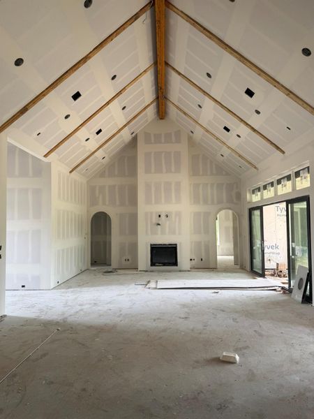 Unfurnished living room with high vaulted ceiling and arched walkways