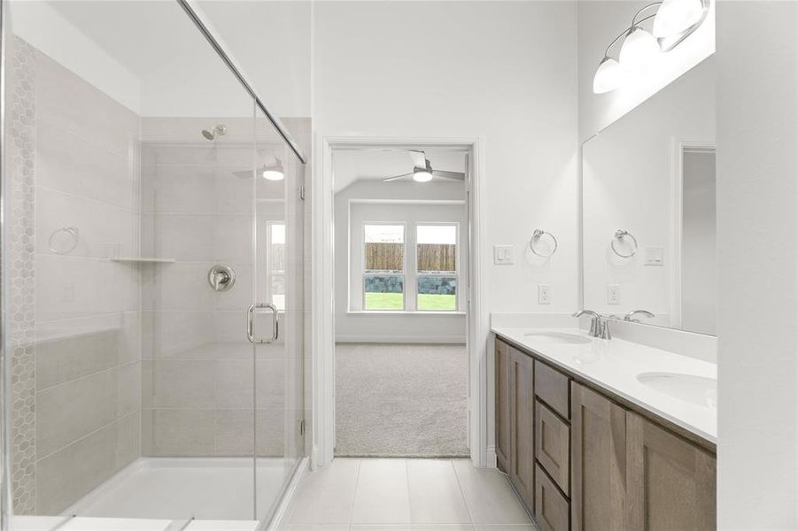 Bathroom with walk in shower, tile flooring, double sink, vanity with extensive cabinet space, and ceiling fan