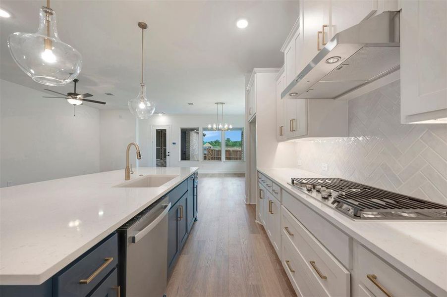 The kitchen features white shaker-style cabinets, a gas stovetop, and a herringbone-patterned tile backsplash