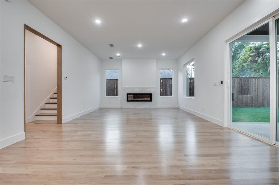 Unfurnished living room featuring light wood-type flooring, a fireplace, recessed lighting, and stairs