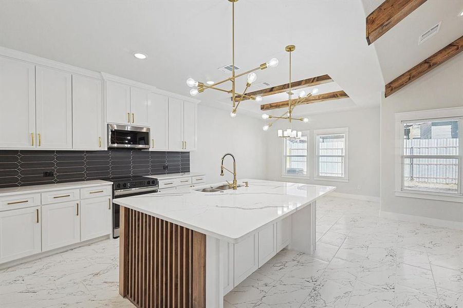 Kitchen featuring sink, hanging light fixtures, stainless steel appliances, a kitchen island with sink, and white cabinets