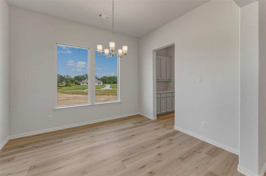 Spacious room featuring wood-finish flooring, light gray walls, and white trim Spacious room featuring wood-finish flooring, light gray walls, and white trim