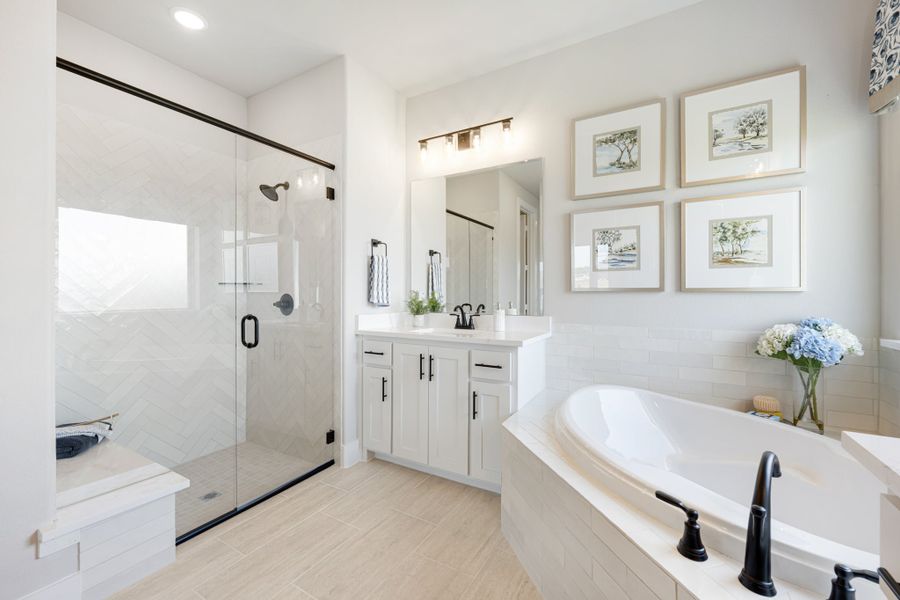 Master bathroom with soaking tub, glass walk-in shower, white vanity, and herringbone tile walls