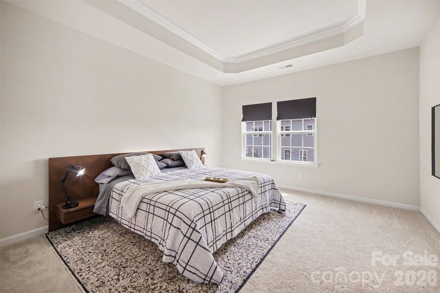 Spacious elegant primary bedroom with tray ceiling