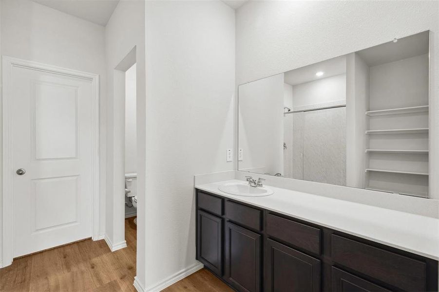 Bathroom featuring a single basin vanity with dark wood cabinetry, a white countertop, and a large mirror