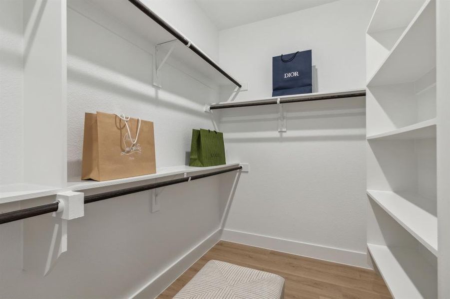 Walk in closet with hardwood / wood-style flooring