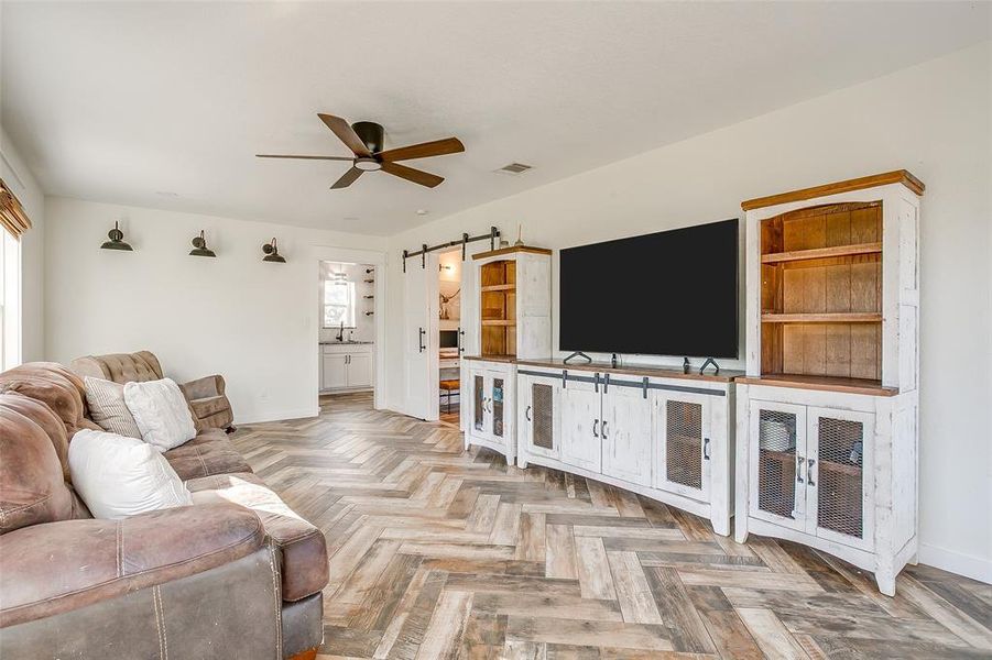 Living area featuring a barn door, parquet floors, and a ceiling fan