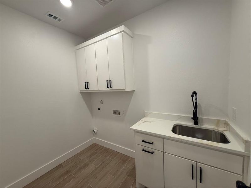 Laundry room featuring wood tiled floors, cabinet space, washer hookup, and electric dryer hookup Laundry room featuring wood tiled floors, cabinet space, washer hookup, and electric dryer hookup