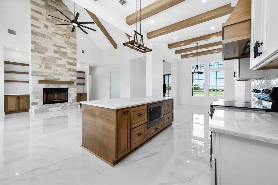 Another angle of the open-concept space, highlighting the spacious living room, floor-to-ceiling stone fireplace, built-ins, and warm wood accents throughout. Another angle of the open-concept space, highlighting the spacious living room, floor-to-ceiling stone fireplace, built-ins, and warm wood accents throughout.