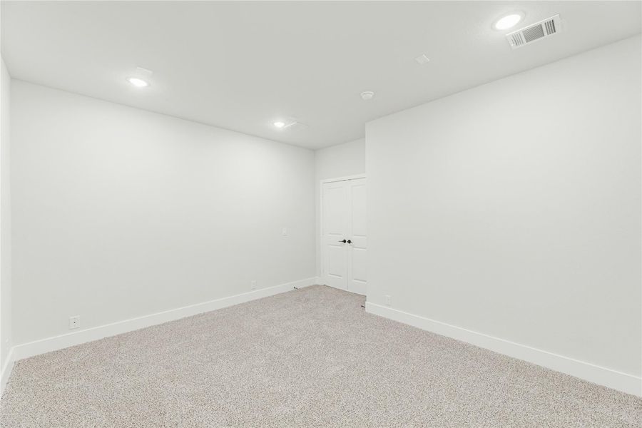 Empty room with white walls, carpet flooring, recessed lighting, and a white door