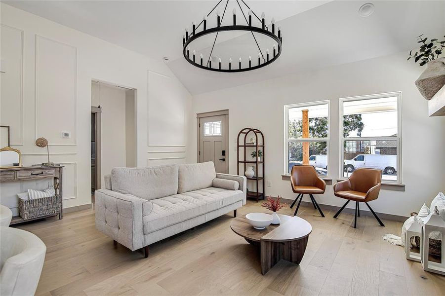 Living room featuring wood-type flooring, a chandelier, and lofted ceiling