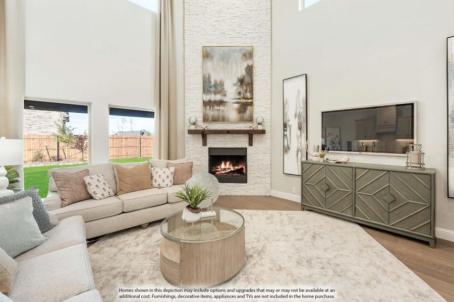 Living room with two-story ceiling, stone fireplace, neutral sectional sofa, and hardwood floors