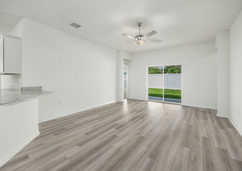 Family room with vinyl flooring and ceiling fan fixture. There is also a sliding glass door that leads to the backyard.