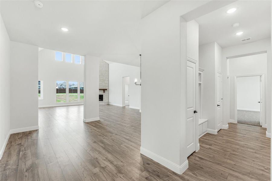 Open-concept living area with hardwood floors, high ceilings, stone fireplace, and large windows