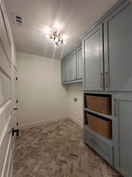 Herringbone-patterned floor tiles complement the light blue cabinetry with brushed nickel hardware