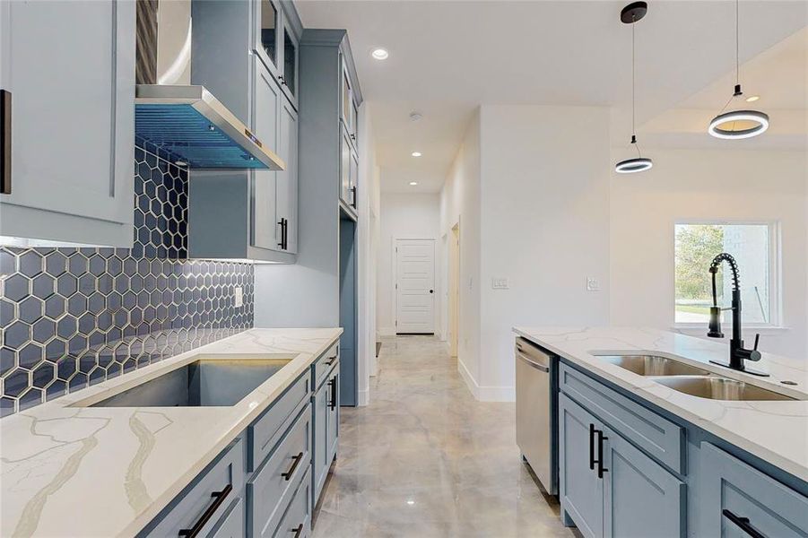 Kitchen featuring tasteful backsplash, light stone counters, stainless steel dishwasher, wall chimney exhaust hood, and sink