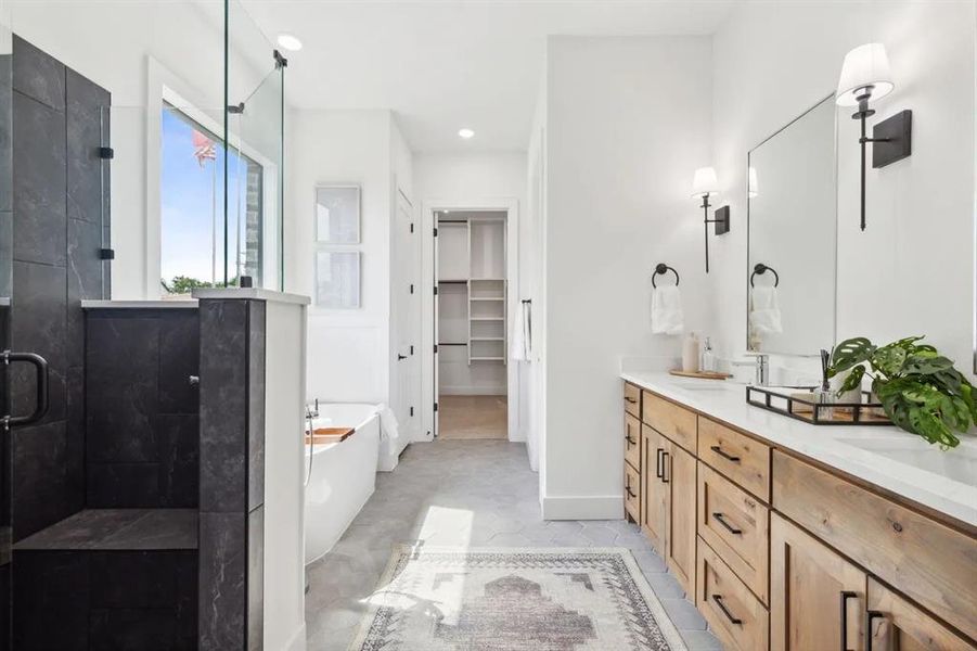 Bathroom featuring a bath, double vanity, a walk in closet, a shower stall, and recessed lighting