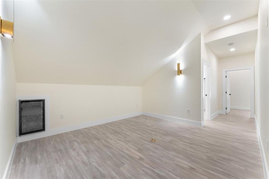 Additional living space featuring vaulted ceiling, light wood-style floors, recessed lighting, and a fireplace