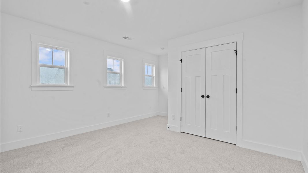 Elegant bedroom retreat featuring soft carpet and oversized windows that create a bright, welcoming space